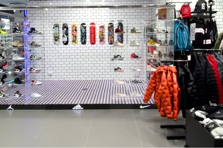 Pavimento LED acceso sotto l'esposizione delle sneaker nello store Offside di Giugliano, con nicchie retroilluminate e teche in plexiglass